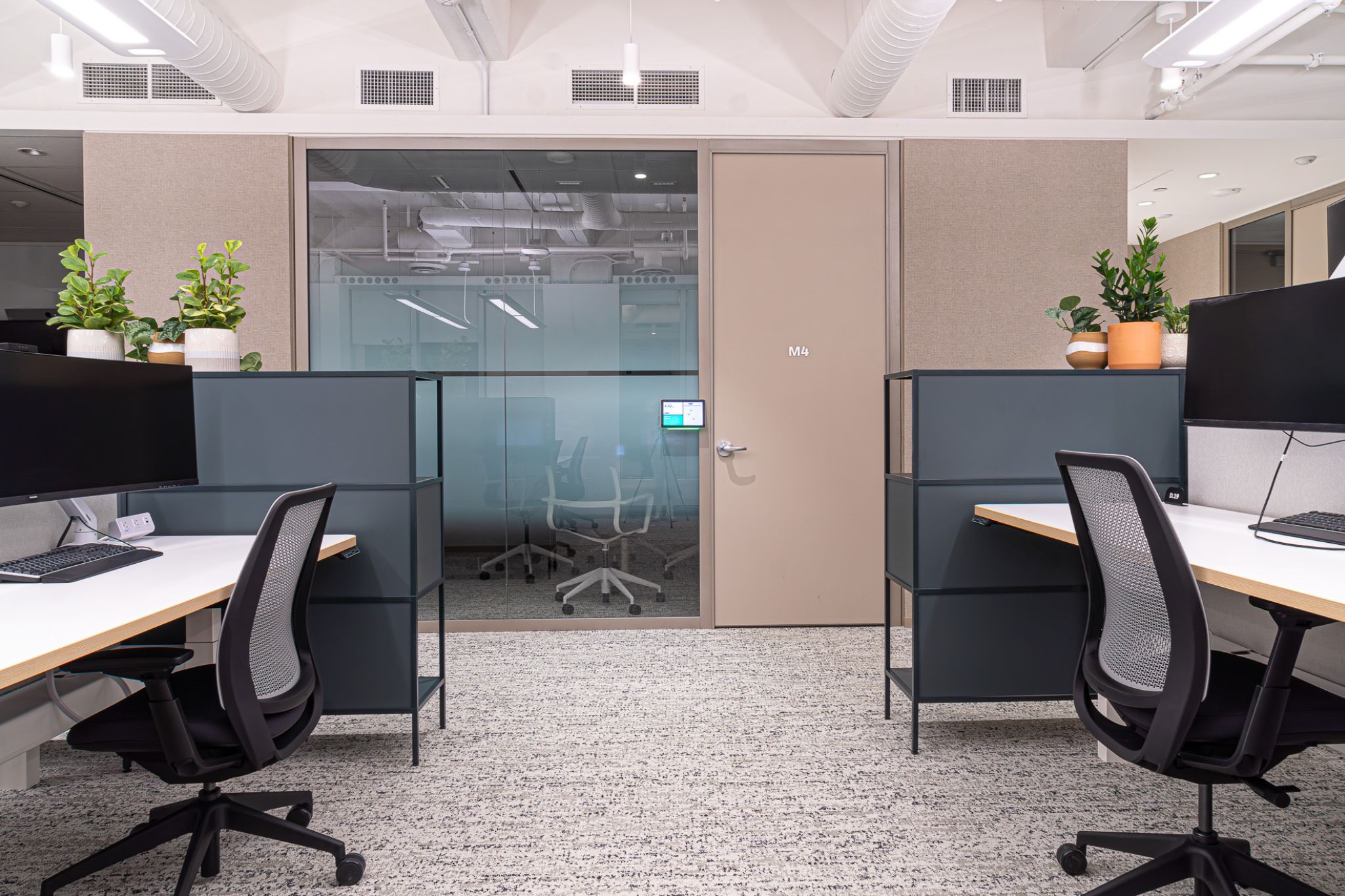 The top of a staircase with a wooden planter to the side and a large TV as you go down the stairs