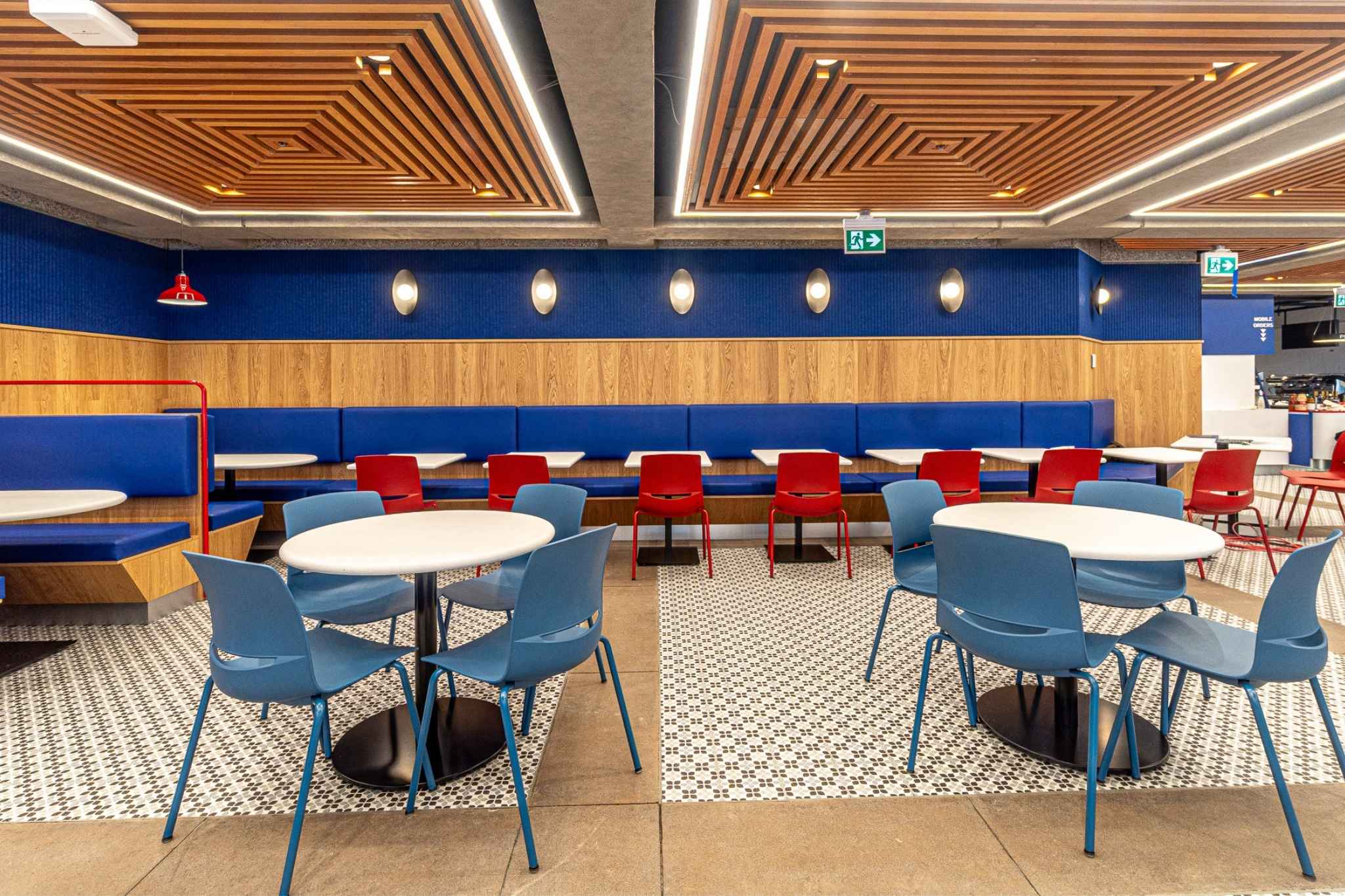 The top of a staircase with a wooden planter to the side and a large TV as you go down the stairs