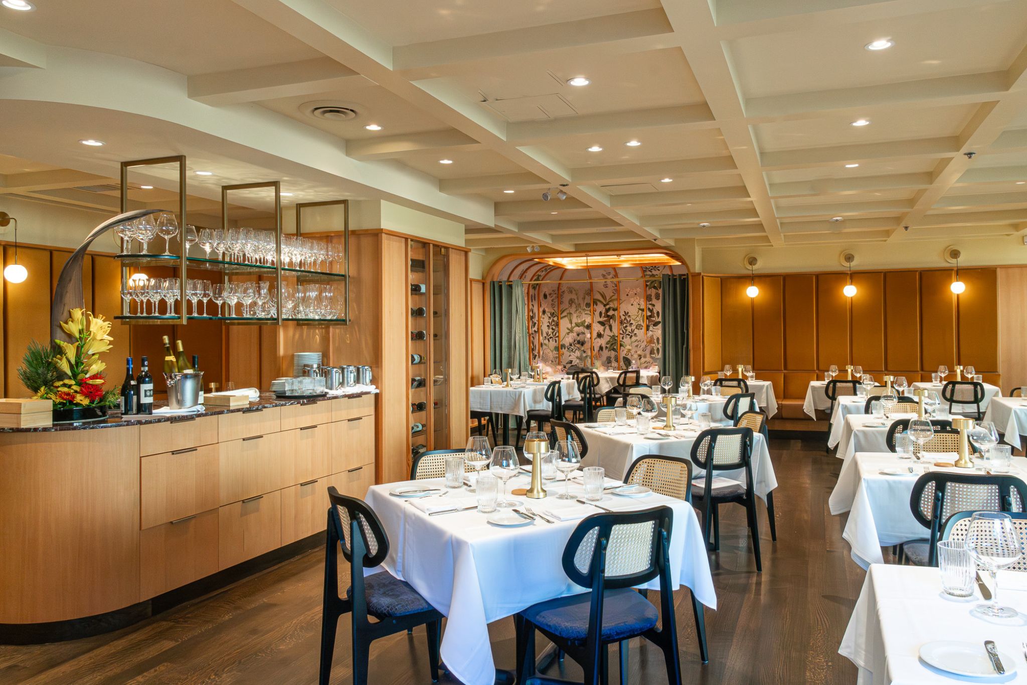 The top of a staircase with a wooden planter to the side and a large TV as you go down the stairs