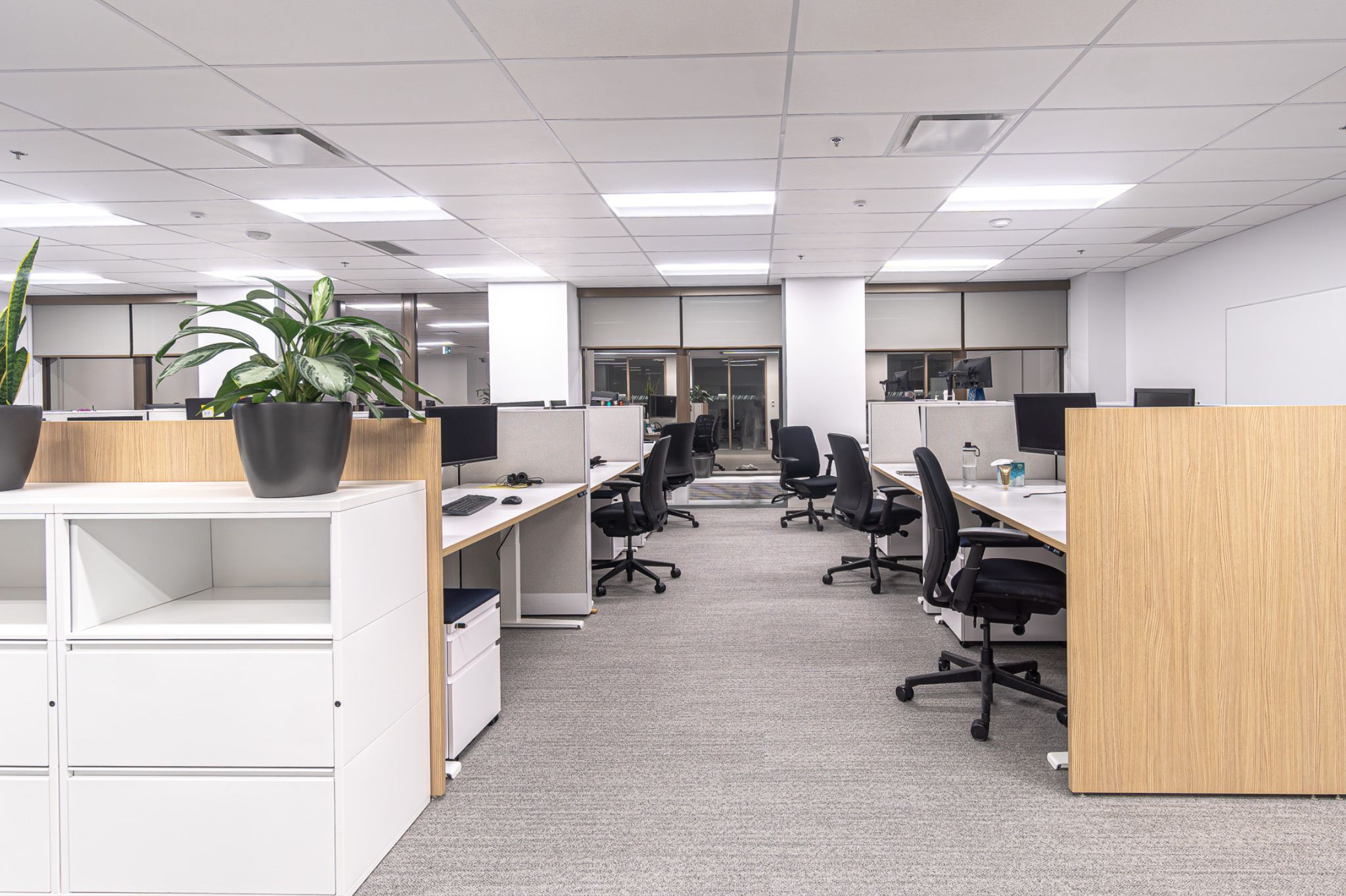 The top of a staircase with a wooden planter to the side and a large TV as you go down the stairs
